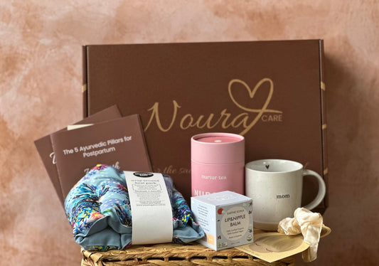 Gift basket with 'Noura Care' branded box, mug, and other items on a textured surface.